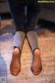 A woman wearing black stockings and jeans standing on a carpeted floor.