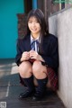 A young woman in a school uniform sitting on a porch.