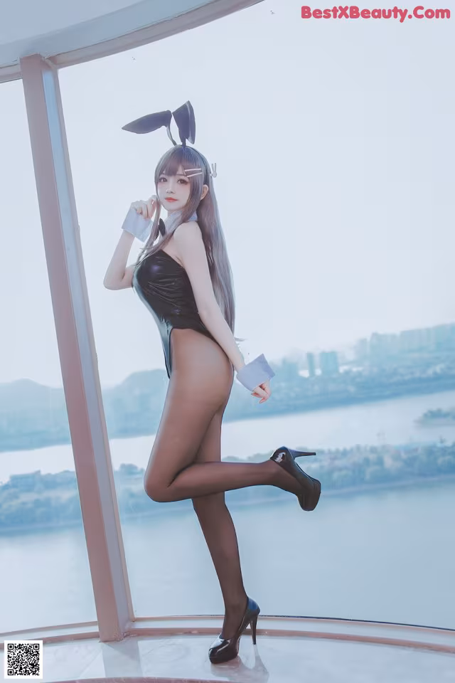 A woman in a bunny costume posing in front of a window.