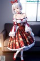 A woman in a red and white dress standing in front of a couch.