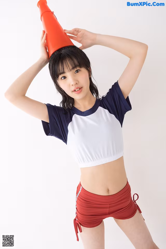A woman in a white and blue top and red shorts holding a red cone.