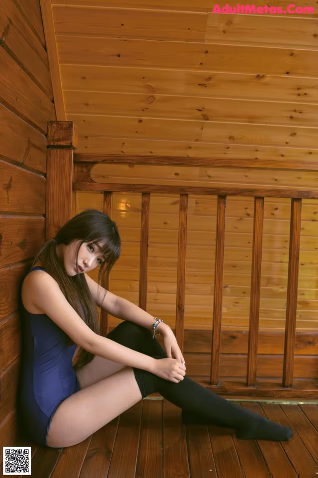 A woman sitting on a wooden floor in a room.