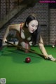 A woman in a red bikini playing pool.