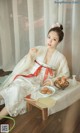 A woman in a white dress sitting on a wooden table.