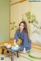 A woman in a blue and white kimono sitting on the floor.