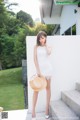 A woman in a white dress and straw hat posing for a picture.