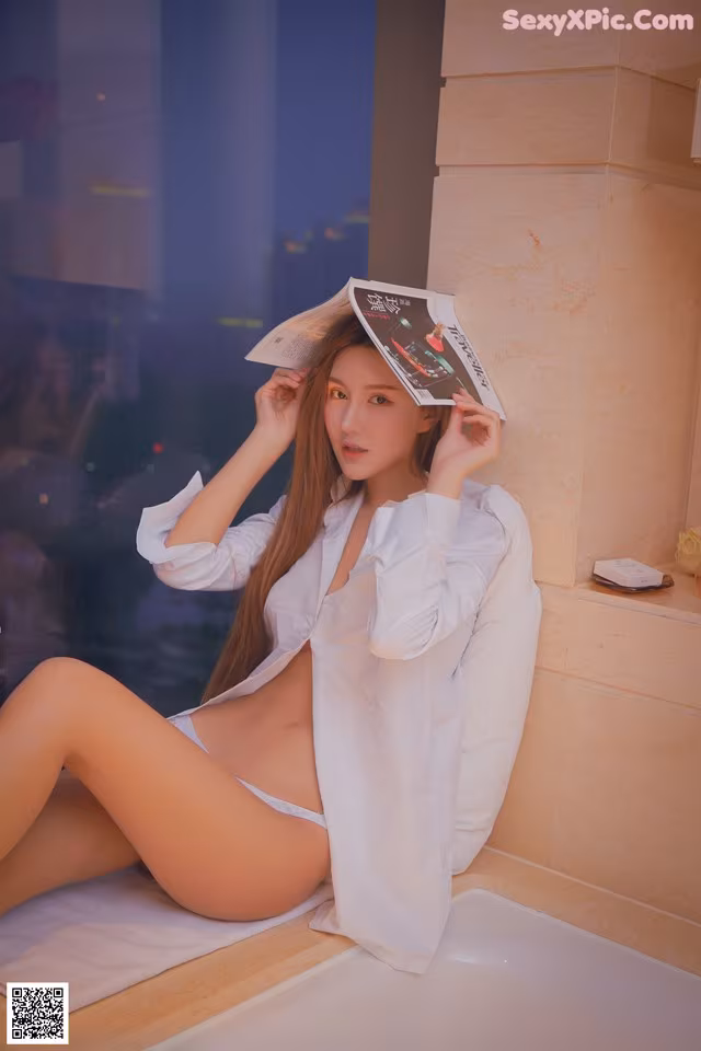 A woman sitting on a bathtub reading a magazine.