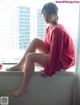 A woman sitting on a window sill next to an apple.