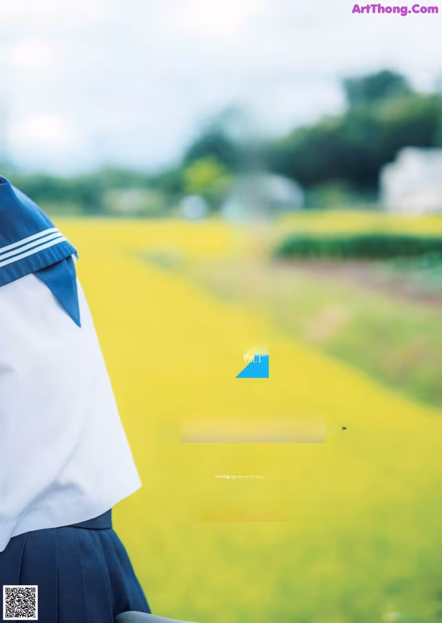 A woman in a school uniform standing in front of a field.