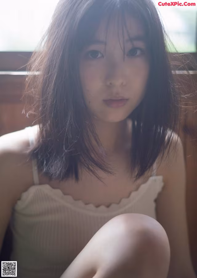 A young woman sitting on a window sill.