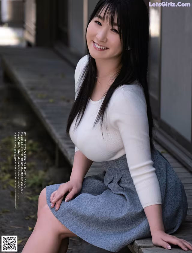A woman sitting on a wooden bench in a skirt.