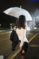 A woman standing in the rain holding an umbrella.