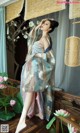 A woman in a blue and pink kimono standing on a wooden floor.
