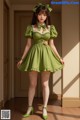 A woman in a green dress and white stockings posing for a picture.