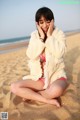 A woman in a pink bikini sitting on the beach.